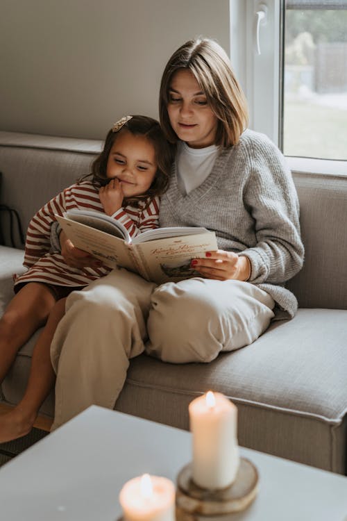 Free A Mother and Daughter Reading a Book on a Couch Stock Photo