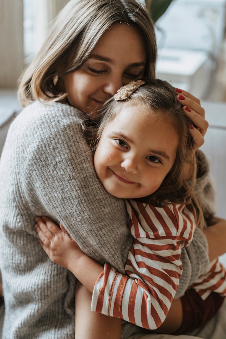 A Mother Hugging And Kissing Her Daughter