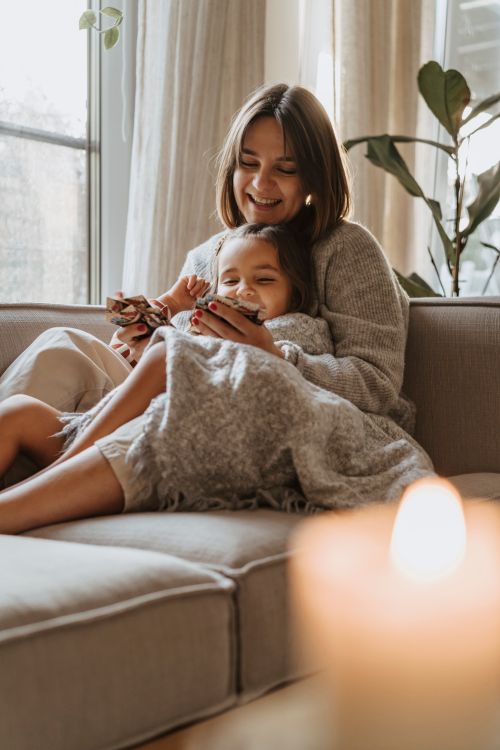Free A joyful mother and daughter bonding indoors, wrapped in cozy blankets, creating a warm atmosphere. Stock Photo