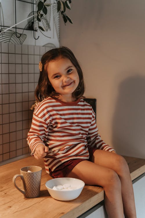 Little Girl Sitting on Kitchen Counter Eating