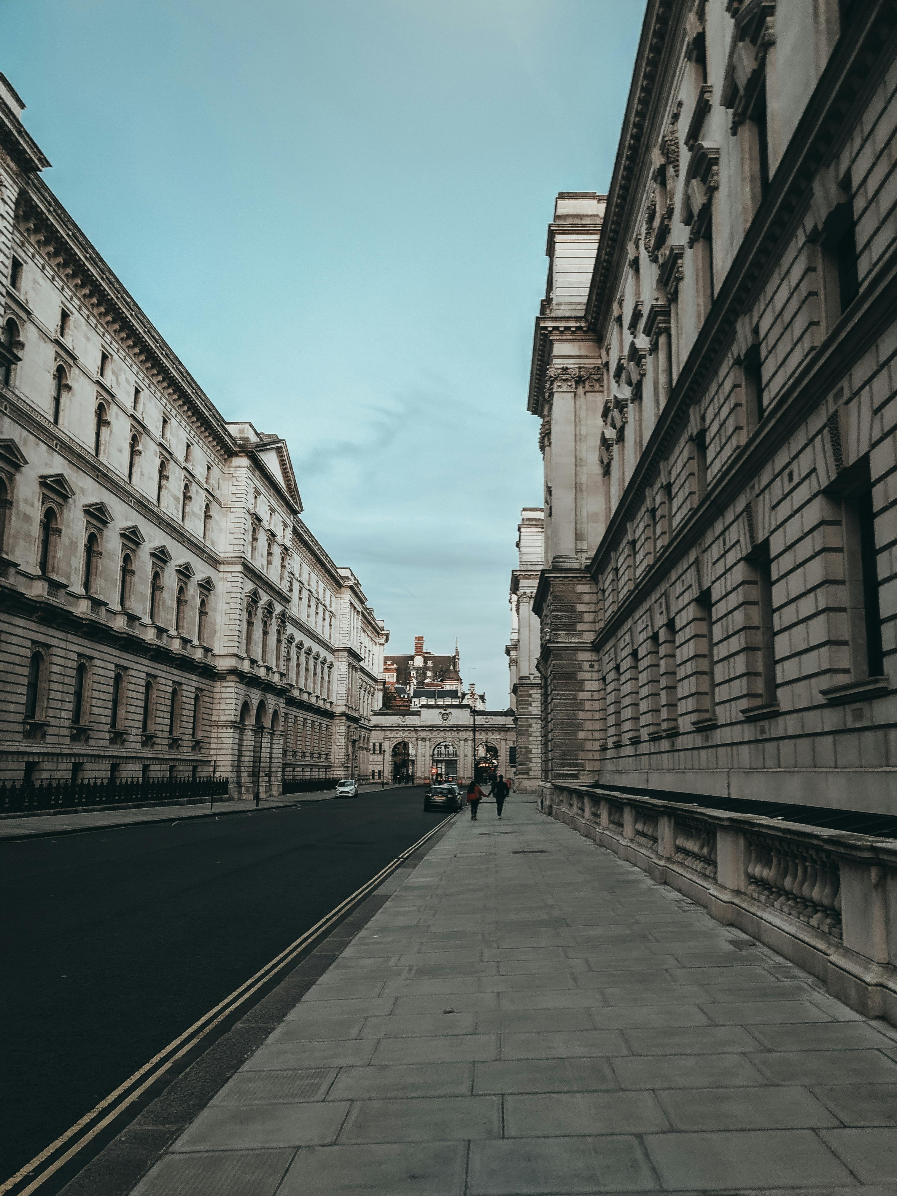 photo of people walking on sidewalk between buildings