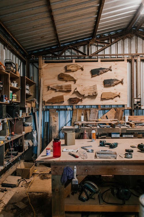 Interior of spacious carpentry with wooden blanks on wall in room with wooden planks and various special instruments on table and shelves