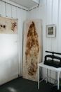 Corner of professional studio with mark of surfboard on dirty textile at wall with frame near metal book press on table