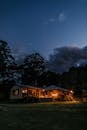 Illuminated house near trees at twilight time