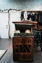 Old fashioned suitcase with various books on wooden box in vintage styled room with white doors and clothes hanging on hangers