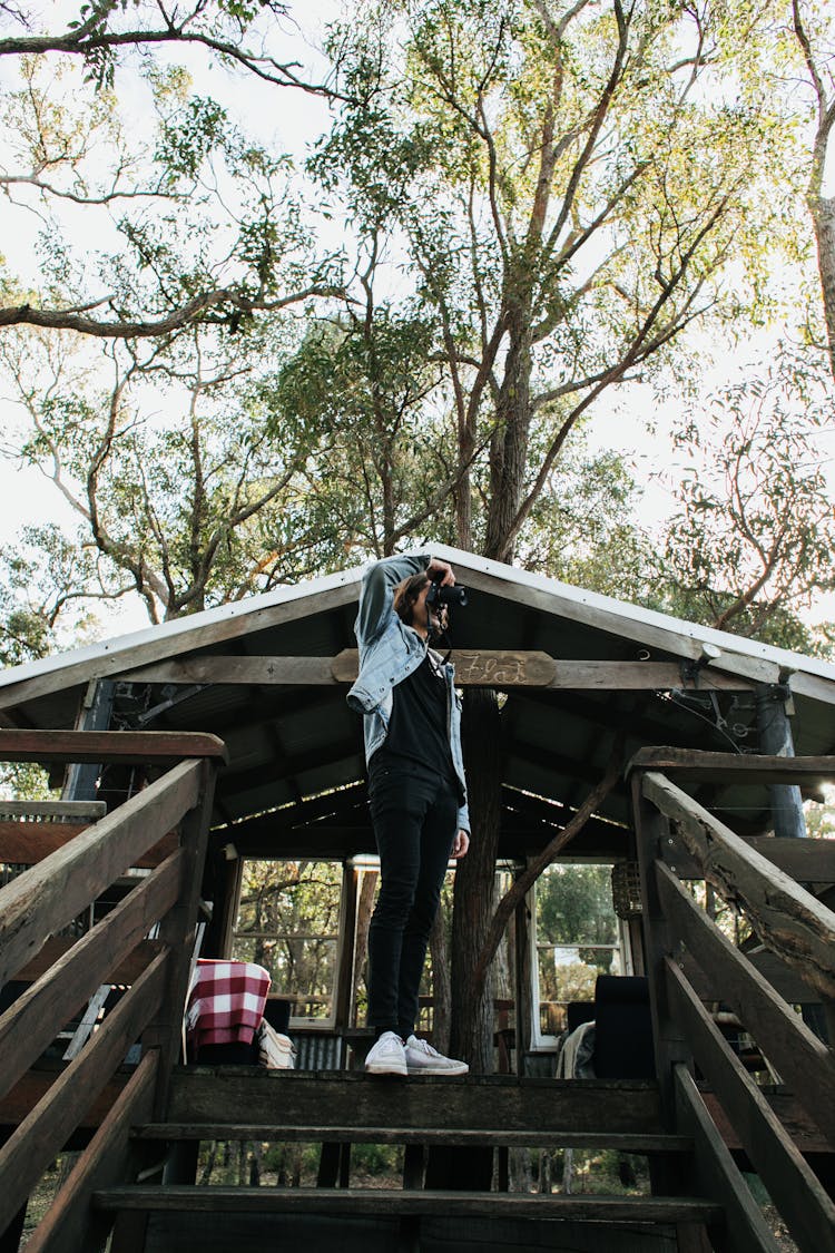 Unrecognizable Woman Taking Photo While Standing On Wooden Steps