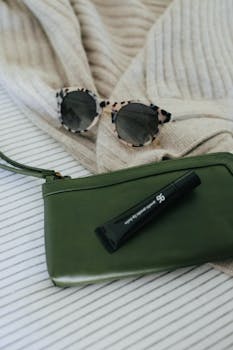 舒适的米色毯子上摆放着时尚配饰，包括太阳镜和包