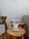 Mug of delicious aromatic hot coffee on timber table composed near books and soft cozy armchairs