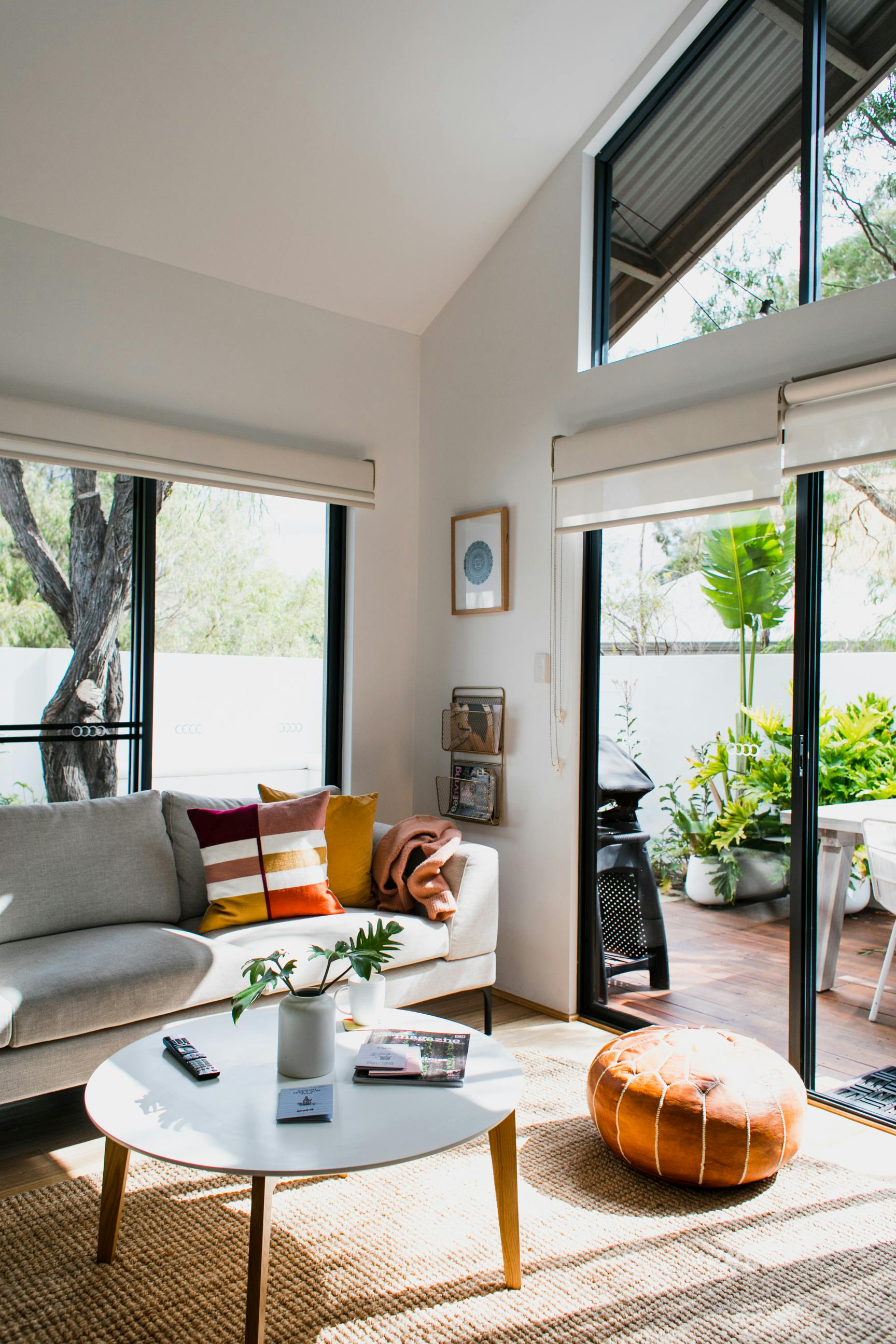 A sunlit modern living room with a cozy sofa and lush outdoor view, creating a warm ambiance.