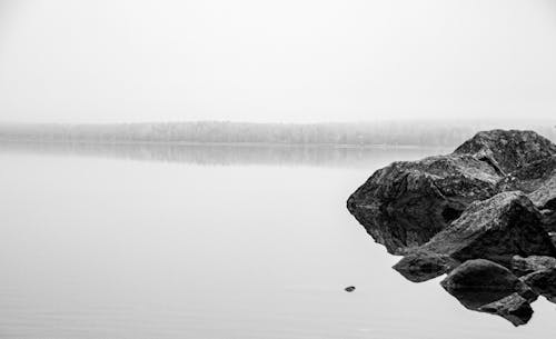 Grayscale Photo of Rocks in Body of Water