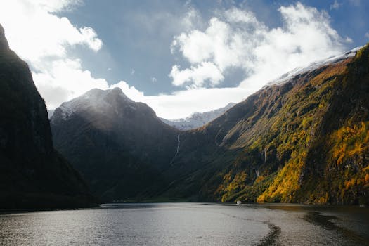 高耸的雪山环绕着宁静的峡湾，在充满活力的天空下，景色令人惊叹