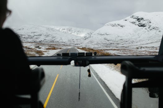 View from a bus through snowy mountains, capturing the serene winter landscape.
