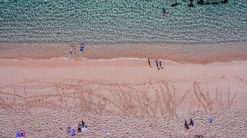 Free People strolling on sandy beach near azure rippling sea Stock Photo