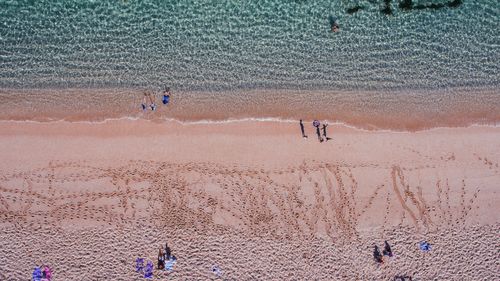 Free Drone view of serene people resting on seashore covered with warm sand and washed by azure crystal clean seawater on sunny weather Stock Photo