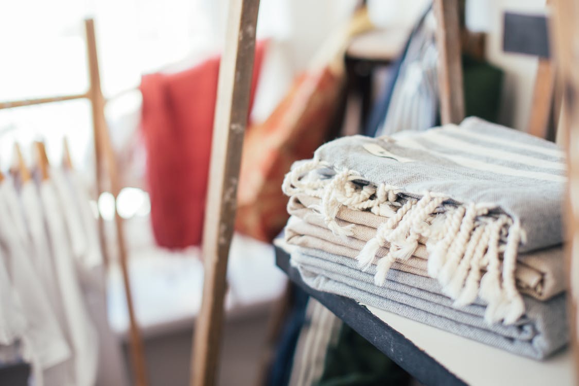 Towels placed on shelf near clothes hanging on rope