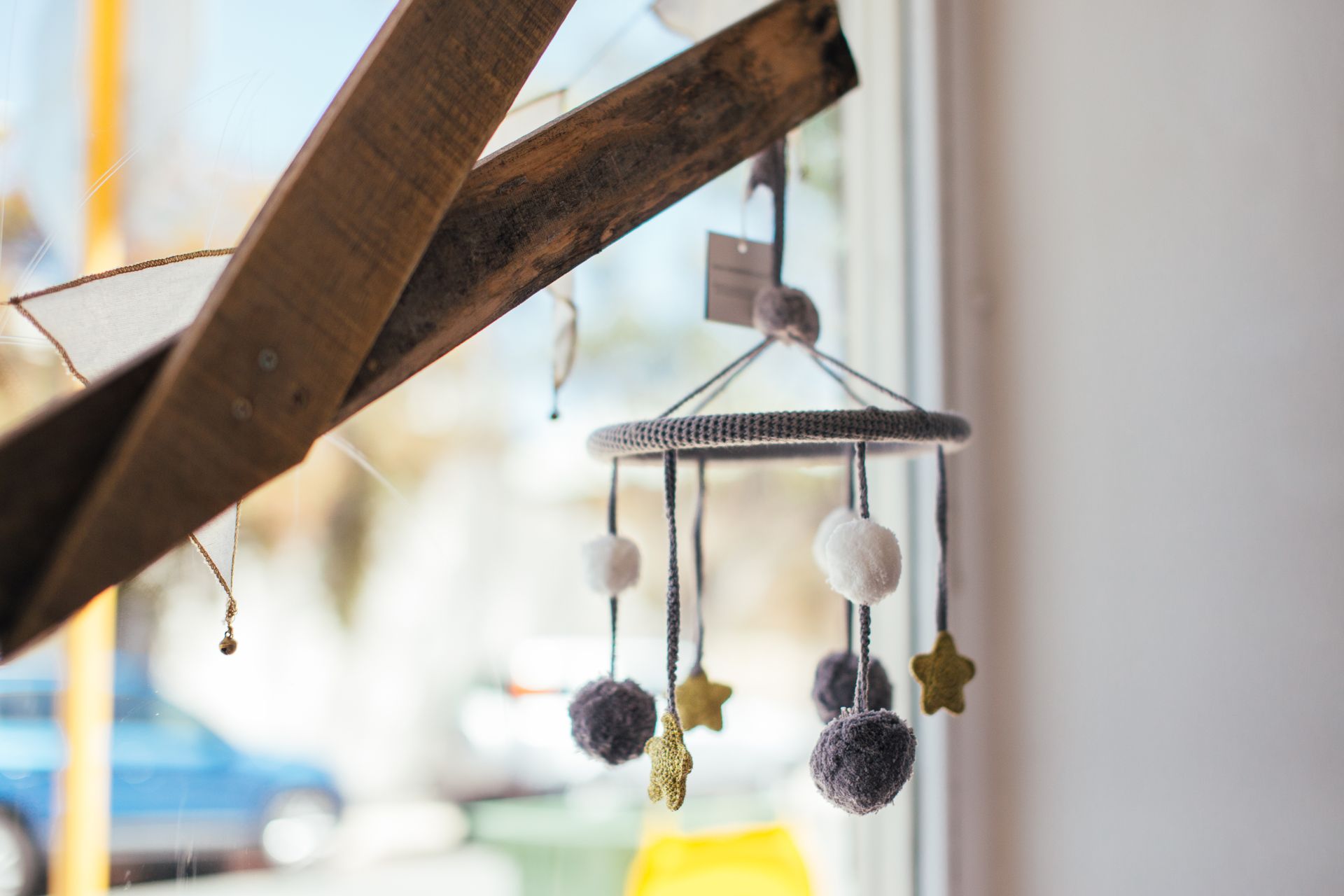 Soft baby mobile hanging on wooden planks near window at home in daytime