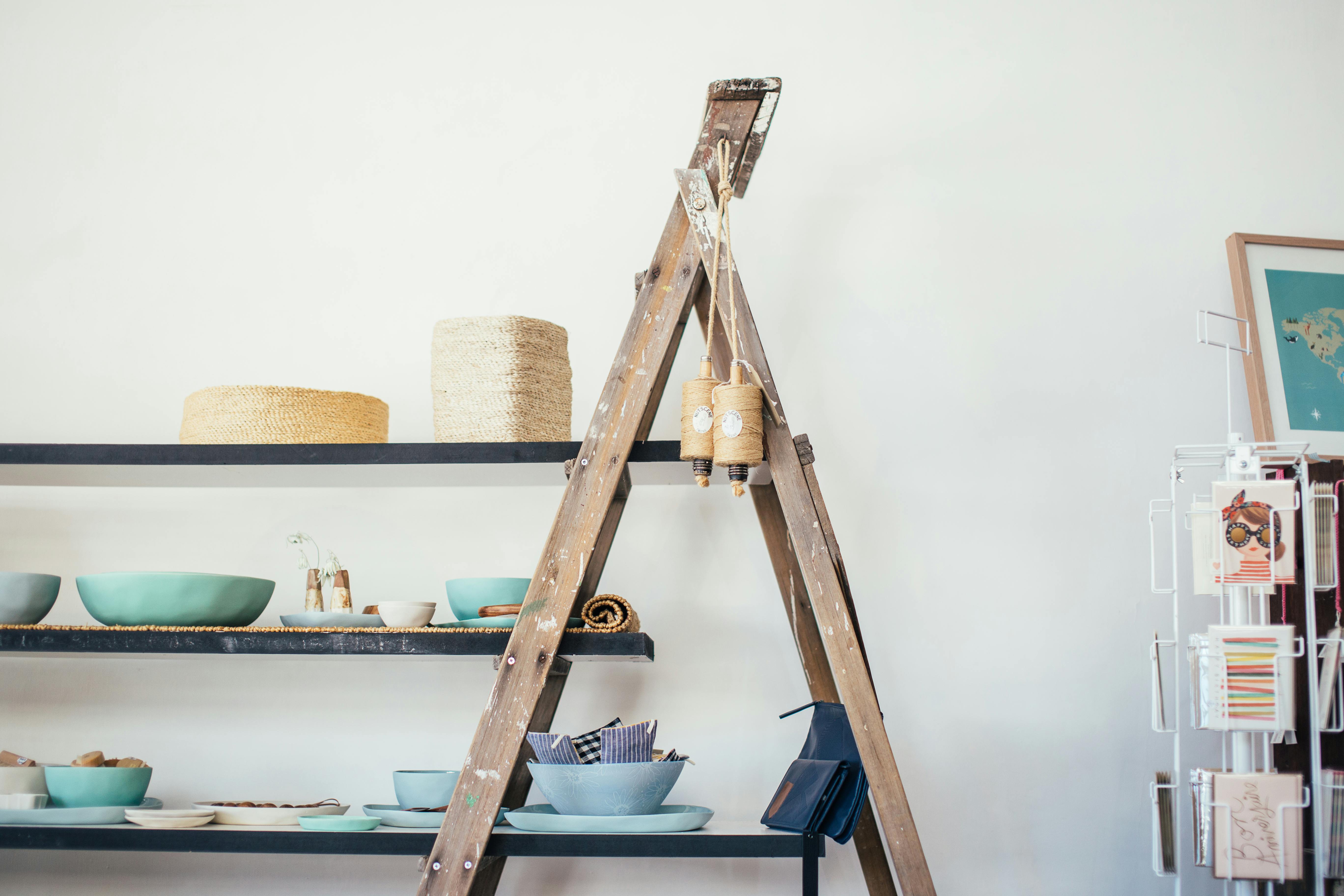 Person using a wooden display ladder to store books and decorative items in a small Bangalore apartment