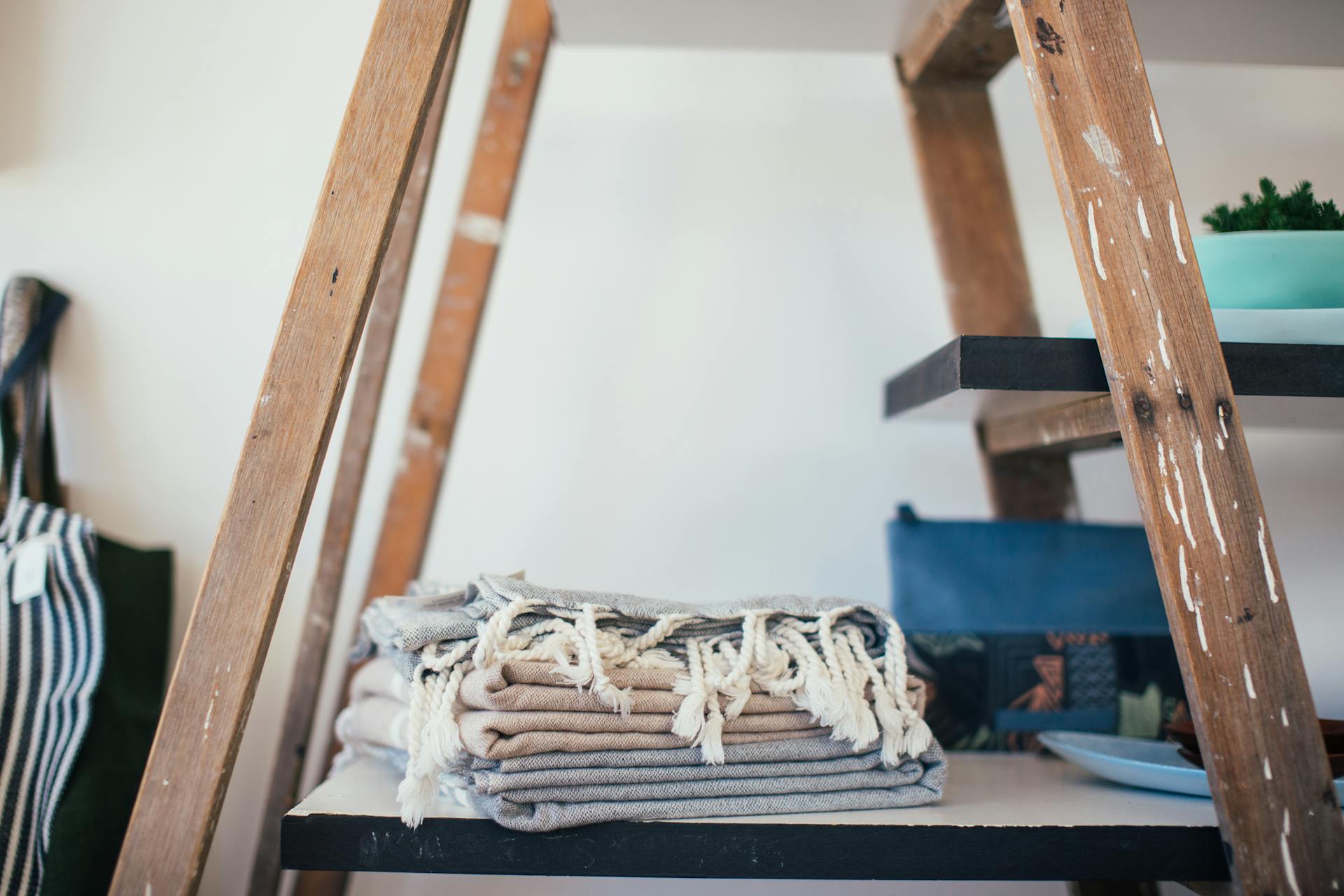 Stack of clean cotton towels with tassels placed on shelf at home in daytime