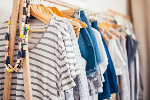 Various feminine clothes placed on timber hangers in modern wardrobe of room in daytime