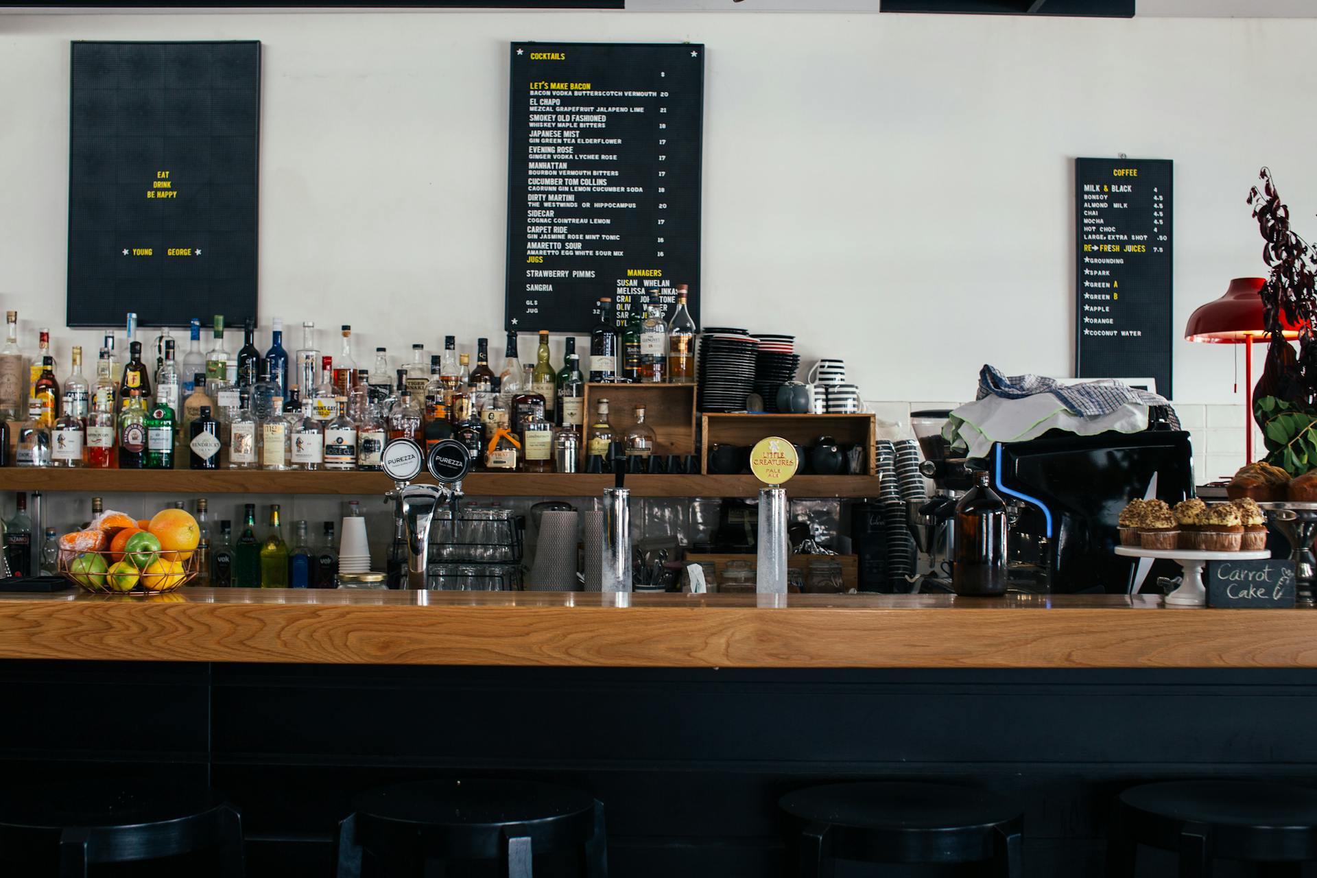 Contemporary cafe with wooden shelves full of many bottles and menu on wall