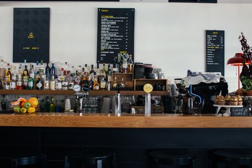 Free Contemporary cafe with wooden shelves full of many bottles and menu on wall Stock Photo