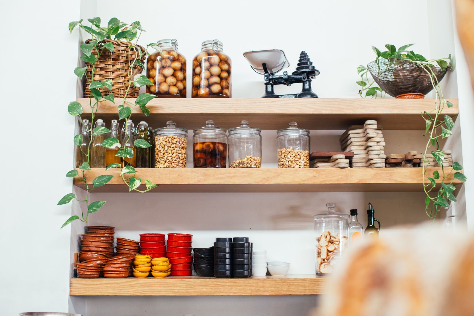 Glass jars of nuts and preserves on wooden shop shelves, beside an old-fashioned counter scale