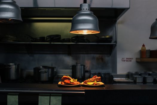 Delicious desserts in plates on table under lamp in dark kitchen of cafeteria