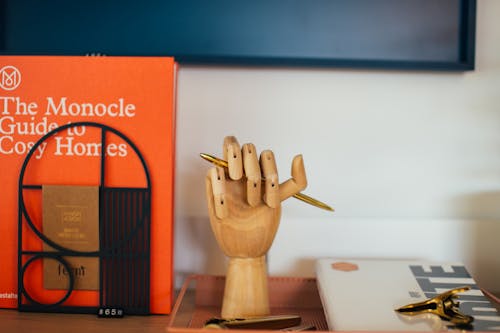 Free Encyclopedia placed near wooden decorative hand shaped pen holder Stock Photo