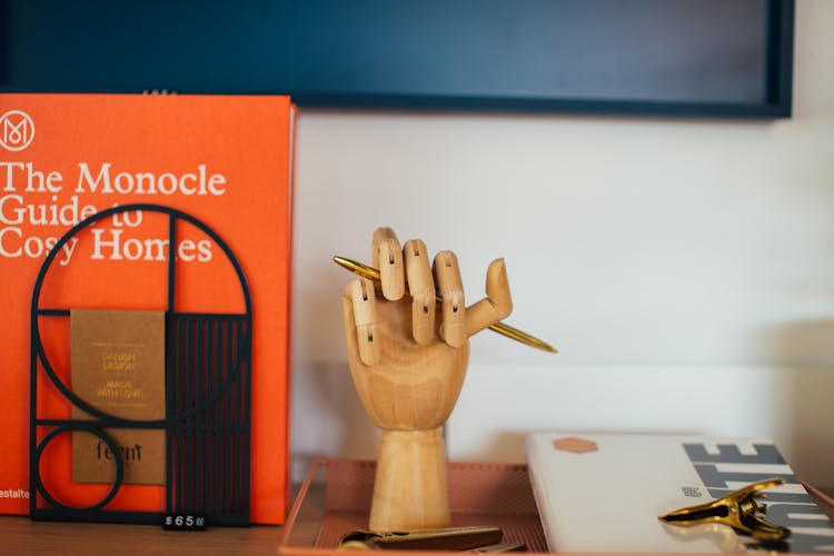 Encyclopedia Placed Near Wooden Decorative Hand Shaped Pen Holder