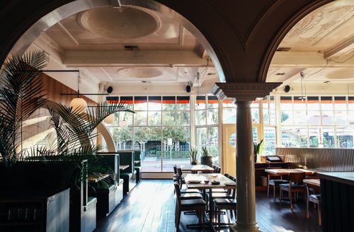 Free Arches with columns and ornamental ceilings in spacious restaurant with glass wall and wooden furniture decorated with exotic potted plants Stock Photo