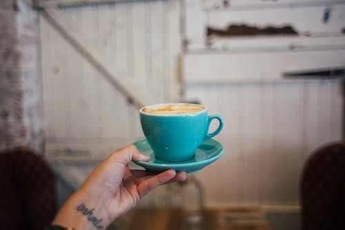 Free Crop woman showing cup of hot cappuccino at home Stock Photo