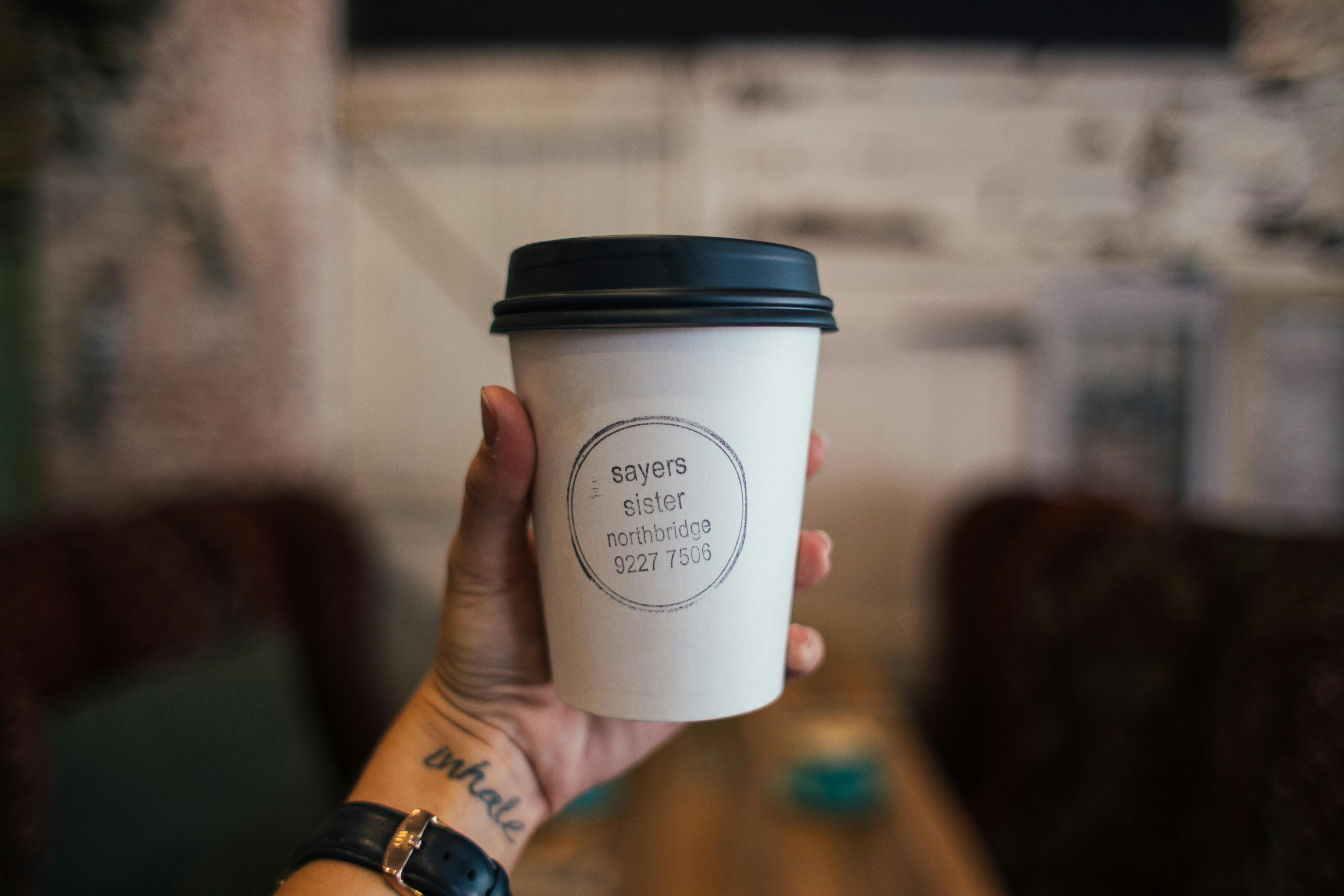 crop faceless woman showing cup of takeaway coffee