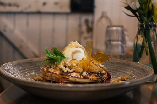 Free Delicious pancaked with caramel and syrup served on plate with ice cream scoop and decorated with fresh mint leaves in cafe Stock Photo