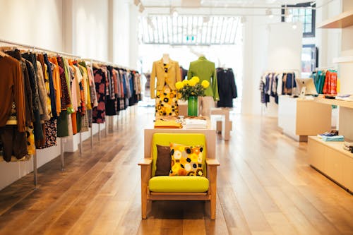 Interior of modern fashion store with stylish colorful clothes handing on rack in daytime