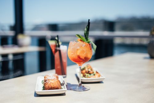 Free Meat loaf served near colorful alcoholic drinks decorated with herbs and straws on table on sunny terrace of cafe against blurred background Stock Photo