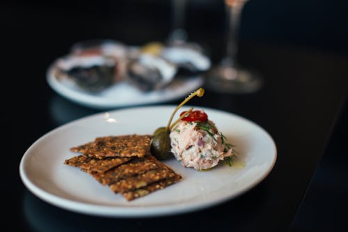 Delicious vorschmack serves on plate with linseed crackers decorated with olives placed on table in modern restaurant on blurred background