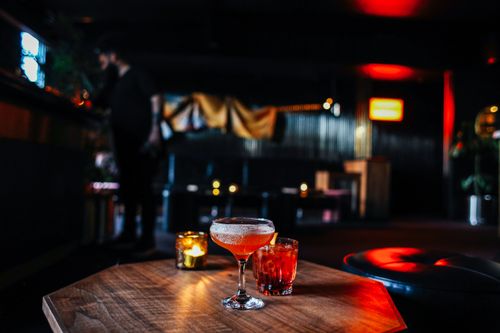 Free Glasses of colorful alcohol beverages and burning candle placed on wooden table in modern cafe with dim light and glowing lamps Stock Photo