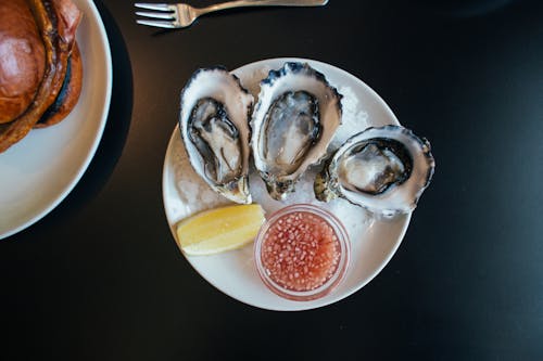 Free Top view of sophisticated seafood dish with oysters served on plate with sauce and lemon on table in modern restaurant Stock Photo