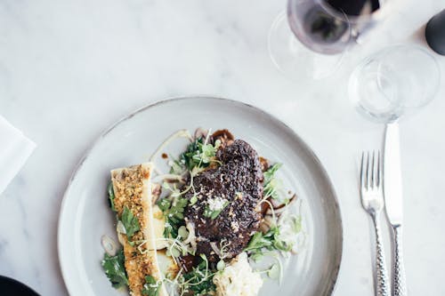 Free Top view of delicious stuffed celery and grilled steal decorated with green herbs served on table with cutlery and glassware Stock Photo