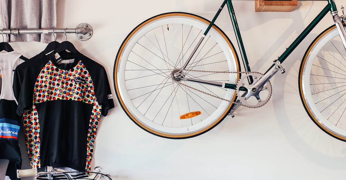 Bicycles at white wall with various t shirts hanging on hangers on metal racks in light room with transport in storage