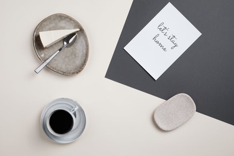 A Coffee And Cake On The Table Top With Printed Paper