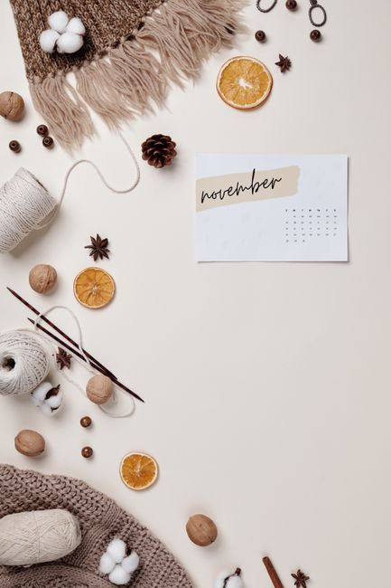 Flatlay featuring knitting materials, dried oranges, November calendar, and autumnal elements.