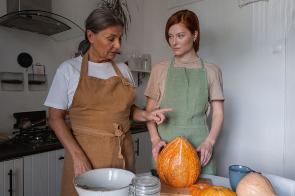 Caregiver helping elderly woman prepare a meal in the kitchen