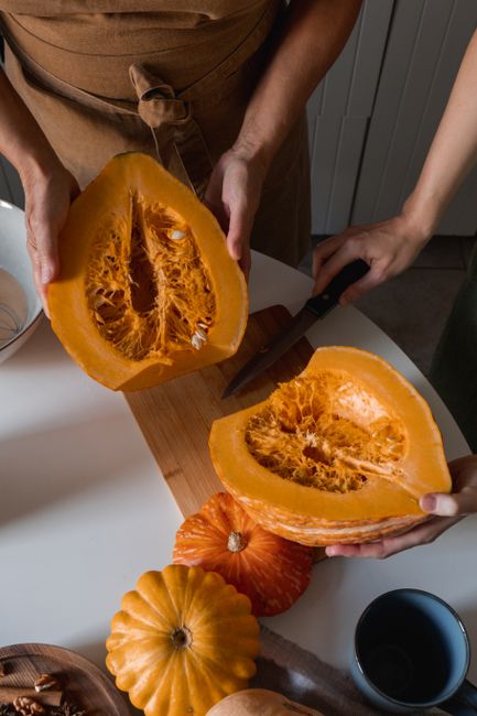 Top view of hands slicing fresh pumpkins, ideal for fall recipes.