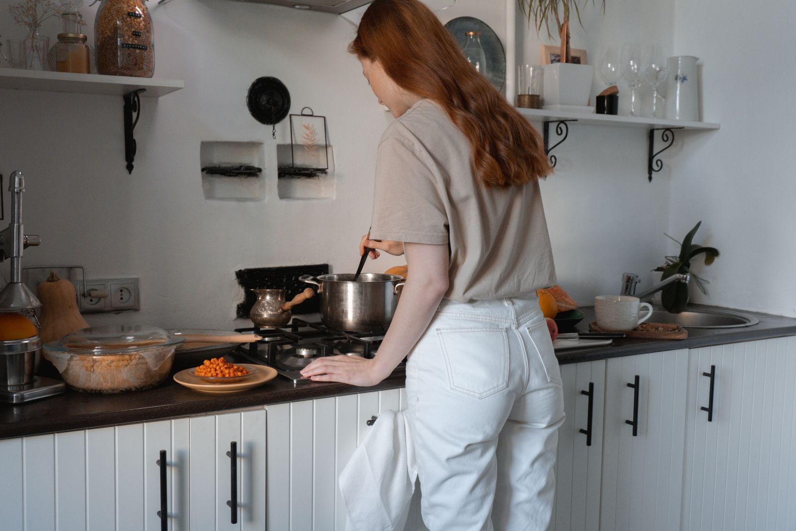 Woman cooking at stove in a cozy modern kitchen setting.