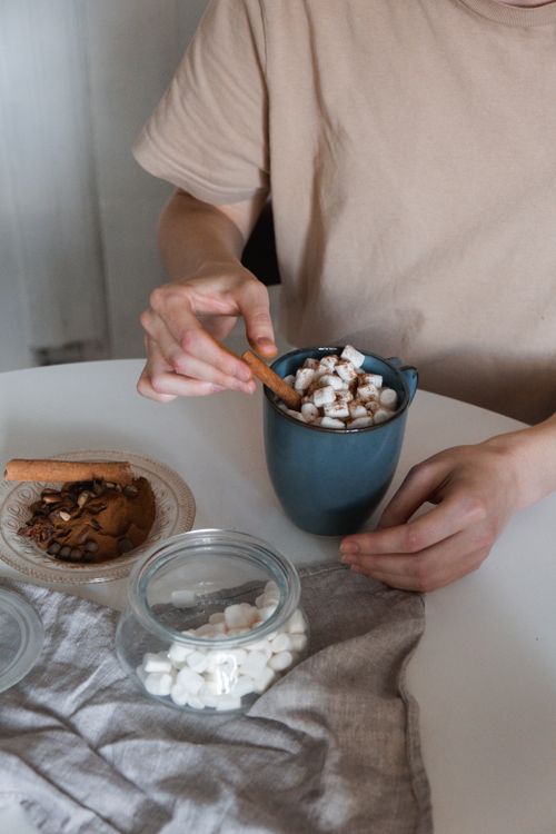 Free Warm and cozy hot chocolate garnished with marshmallows and cinnamon stick, perfect for a chilly day. Stock Photo