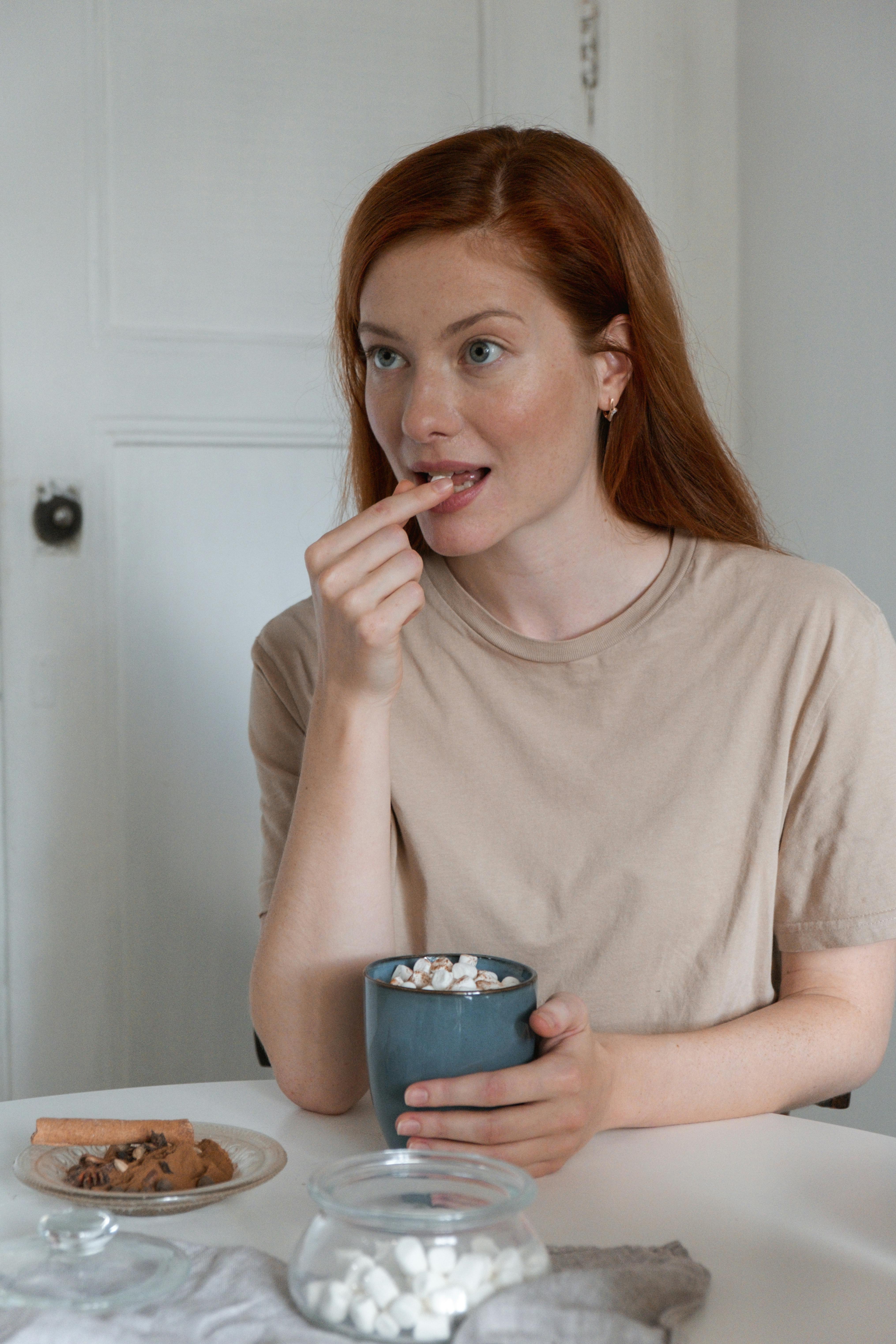 woman sittin on table holding a blue ceramic cup