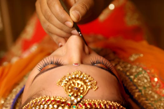 Detail view of traditional Indian makeup application with ornate jewelry and bright attire.