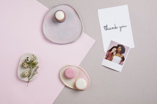 Free A minimalist flat lay with pink and white macarons, thank you card, and Polaroid photo on a pastel background. Stock Photo