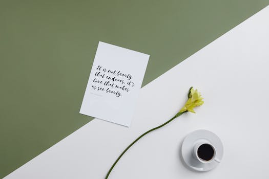 Minimalist flat lay with coffee cup, yellow flower, and motivational quote card on a green and white background.